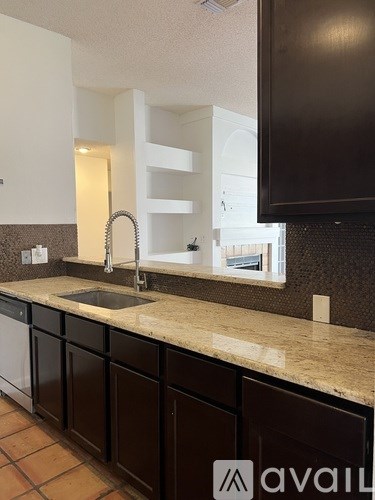 A kitchen with brown cabinets and a marble countertop.