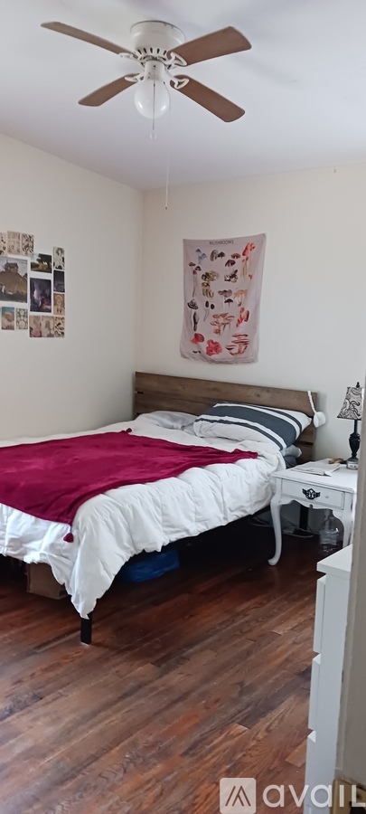 A bedroom with a bed, a ceiling fan, and pictures on the wall.
