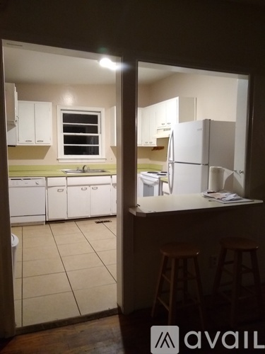 A kitchen with white cabinets and a counter with a bar stool.