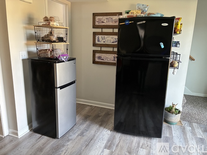 A black fridge stands next to a white fridge in a kitchen.