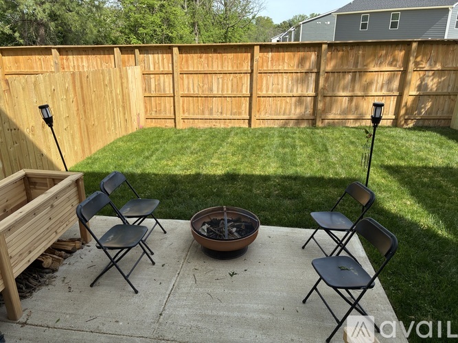 A backyard with a fire pit and chairs.
