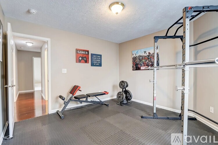 A room with a gym setup including a bench, weights, and a pull-up bar.