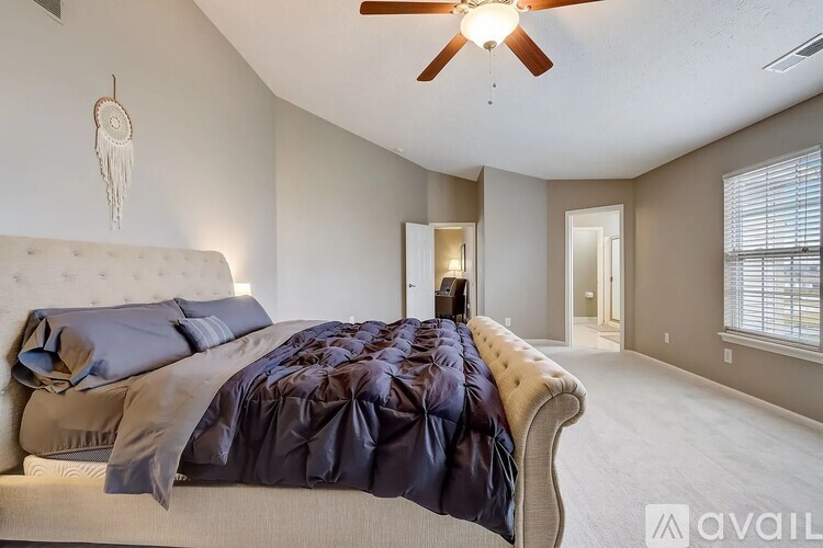 A bedroom with a large bed and a ceiling fan.