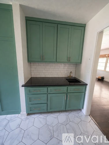 A kitchen with green cabinets and a black countertop.