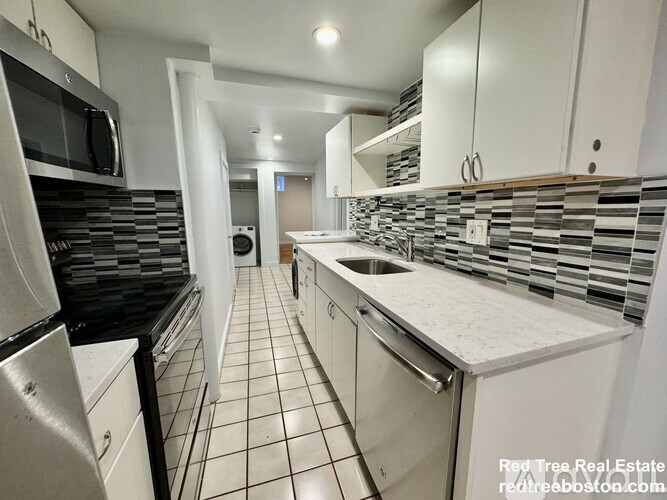 A kitchen with white cabinets and black appliances.