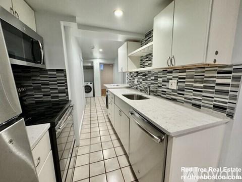 A kitchen with white cabinets and black appliances.