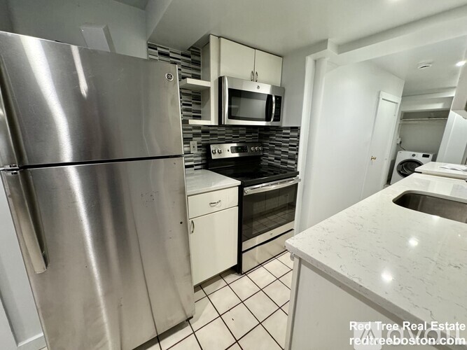 A kitchen with a stainless steel refrigerator and a white countertop.