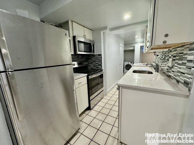 A kitchen with a refrigerator, microwave, and oven.