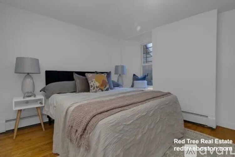 A bedroom with a bed, nightstand, and lamp.