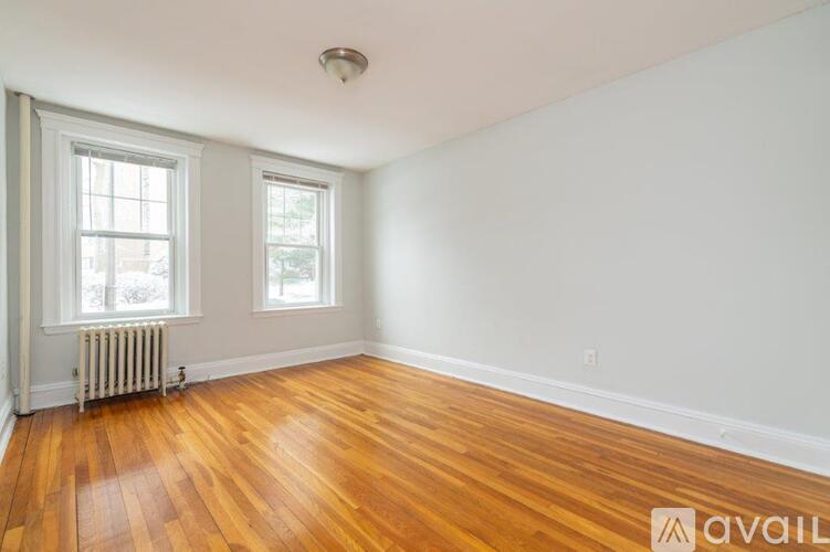 A room with wooden floors and two windows.