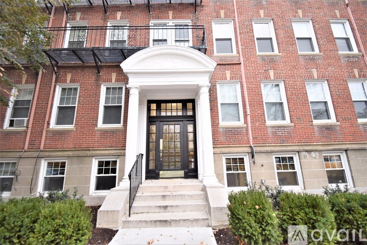 A red brick building with a black door and steps leading up to it.