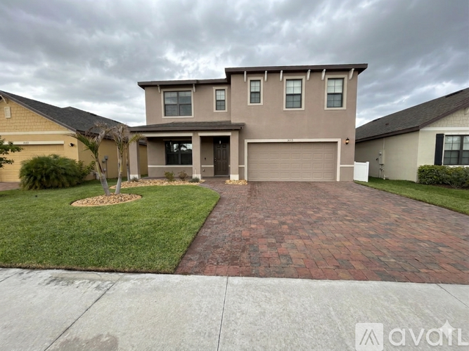 A house with a grey garage door and a brick driveway.