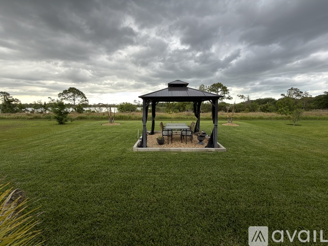 A gazebo sits in the middle of a grassy field.