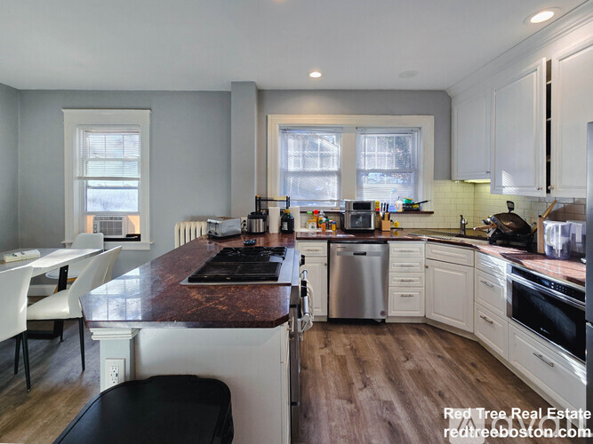 A kitchen with a black stove top and white cabinets.