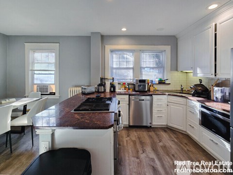 A kitchen with a black stove top and white cabinets.
