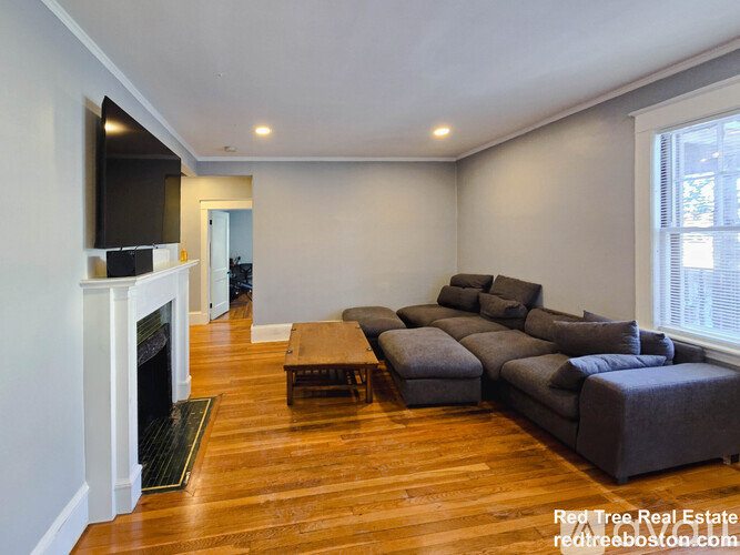 A living room with a grey couch and a fireplace.