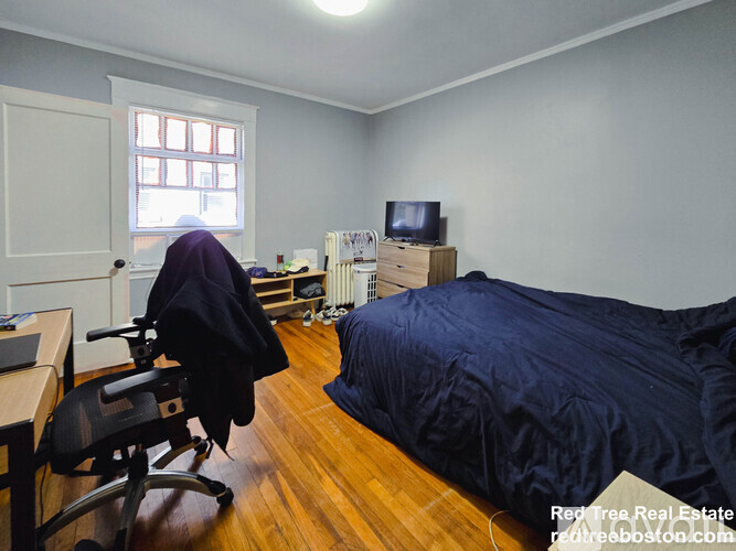 A bedroom with a bed, chair, and window.