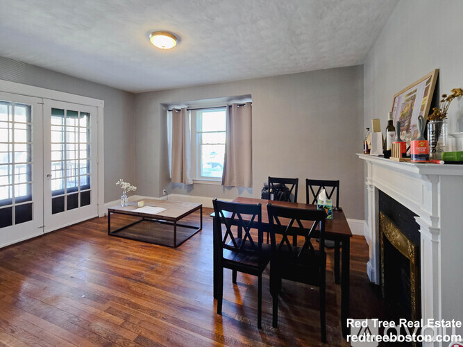 A living room with a fireplace and a dining table.