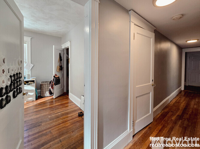 A hallway with a white door and a white wall.