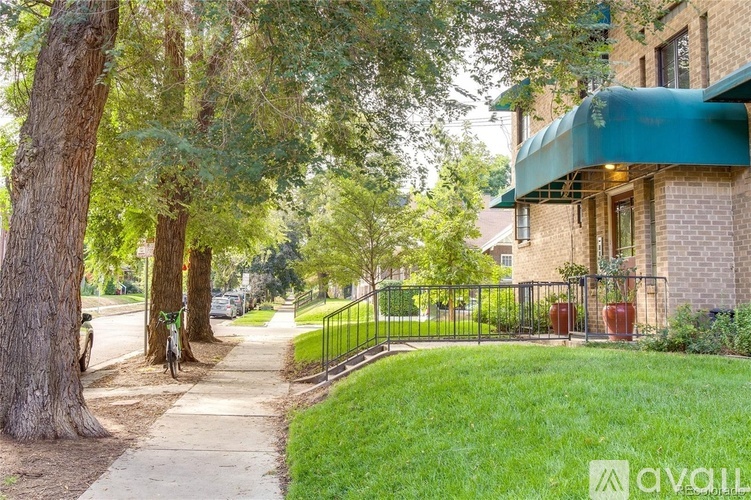 A tree-lined street with a brick building and a green awning.