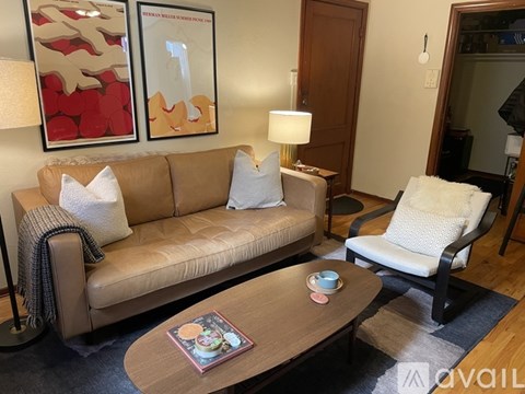 A living room with a couch, chair, and two framed pictures on the wall.