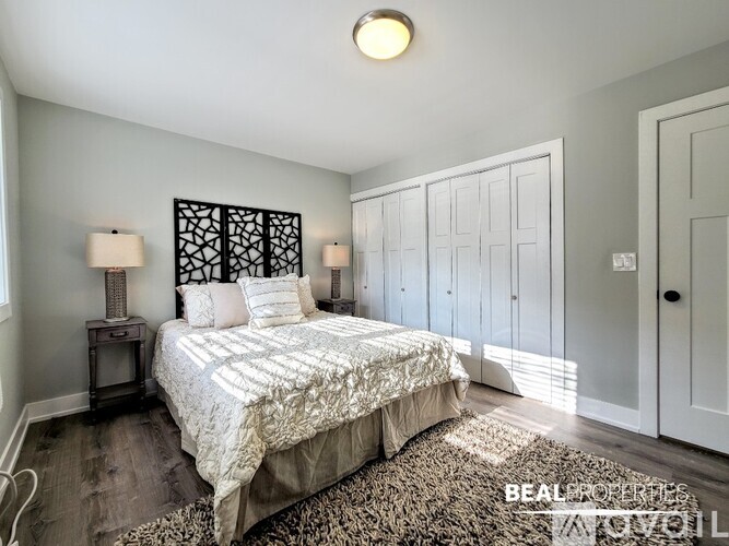 A bedroom with a bed, two lamps, and a wall hanging.