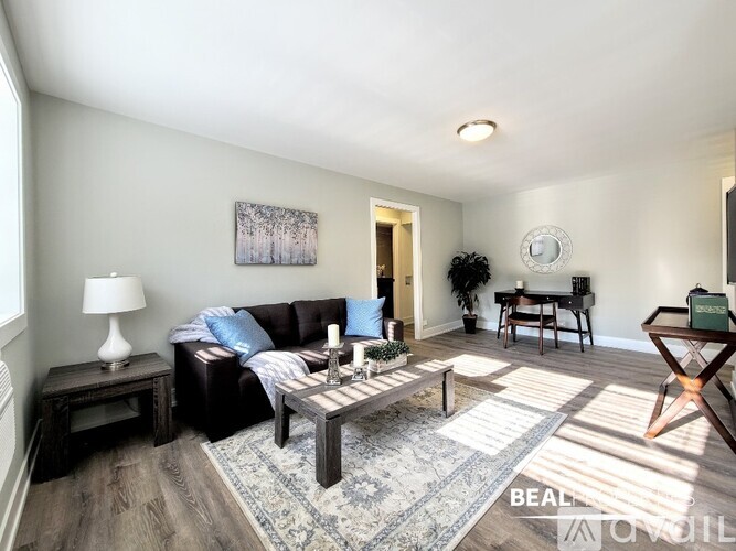 A living room with a black couch, a wooden coffee table, and a painting on the wall.