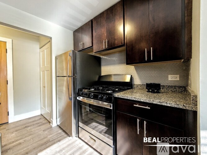 A kitchen with dark brown cabinets and a stainless steel refrigerator.