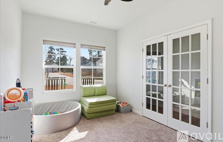 A room with a window seat and a green ottoman.