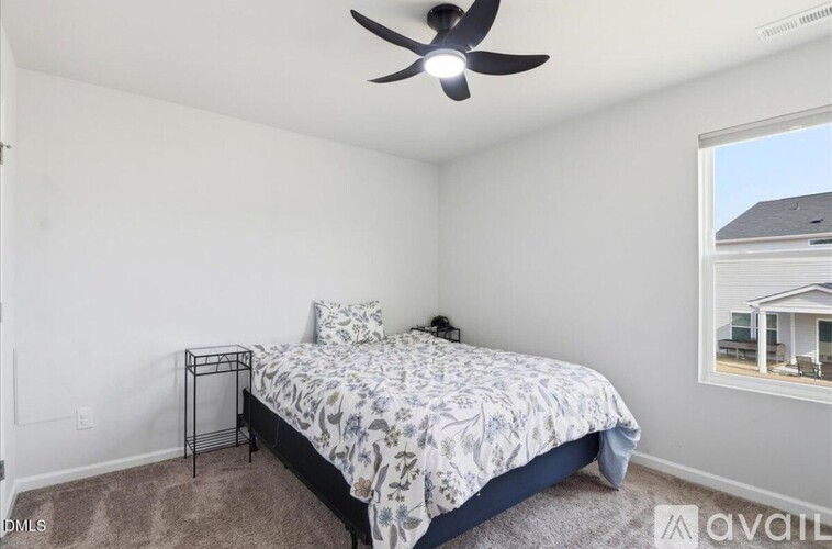 A bedroom with a bed, a fan, and a window.