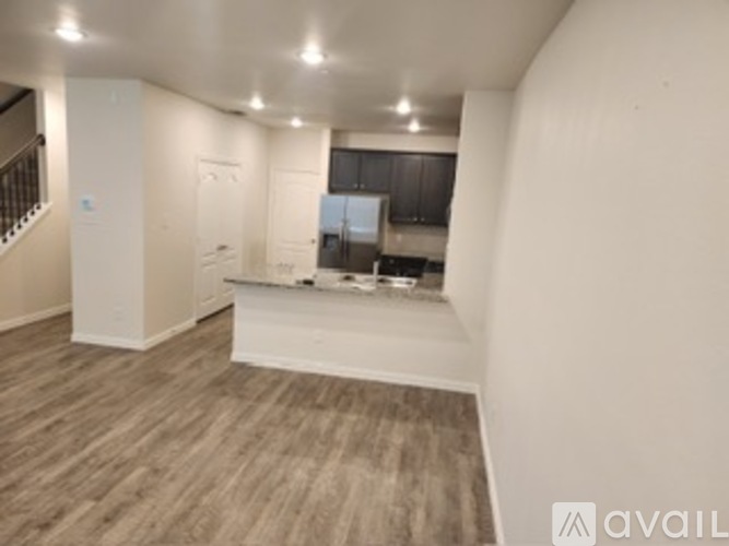 A spacious room with wooden flooring and white walls.