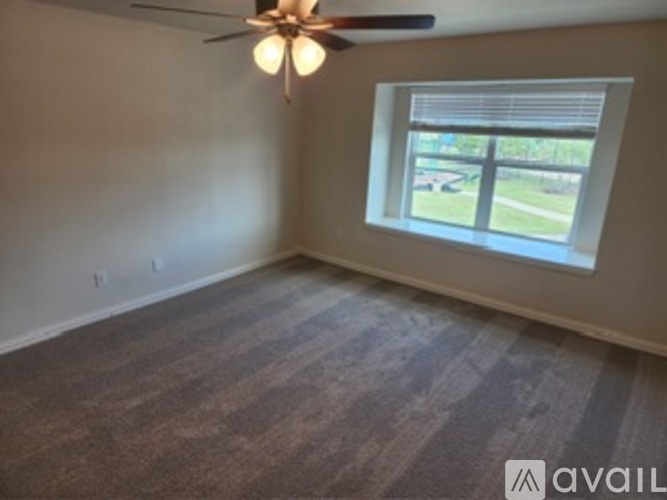 A room with a ceiling fan and a window with blinds.