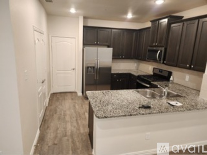 A kitchen with dark brown cabinets and a granite countertop.