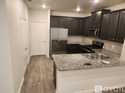 A kitchen with dark brown cabinets and a granite countertop.