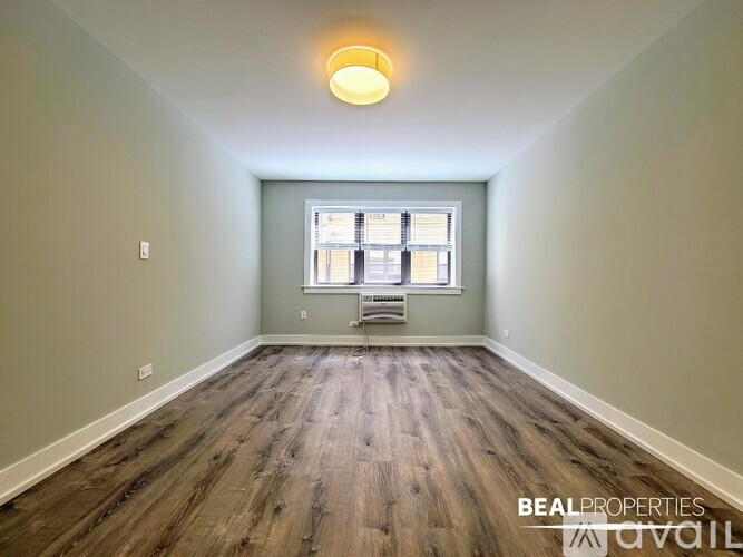 A room with wooden flooring and a window with blinds.