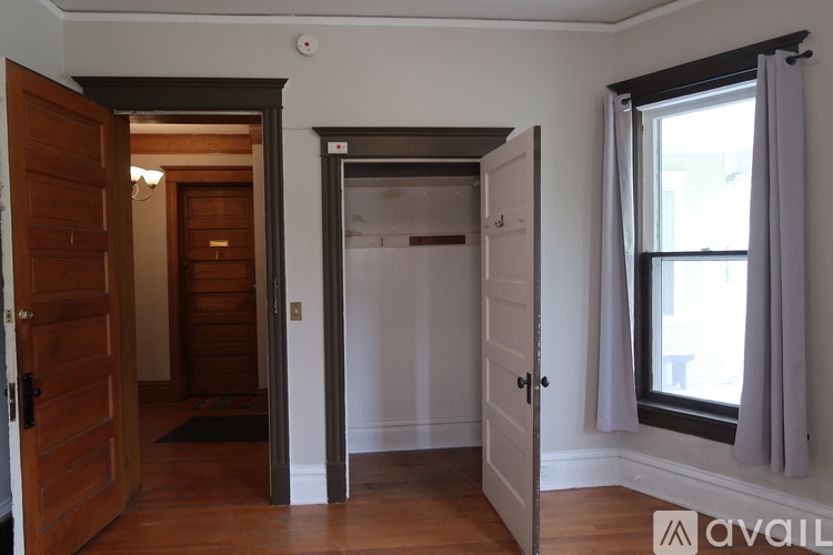 A room with a doorway leading to another room, a window with curtains, and a mat on the floor.