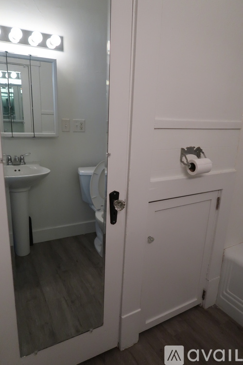 A bathroom with a toilet, sink, and mirror.