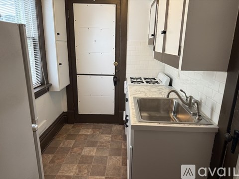 A kitchen with a white fridge, sink and brown tiles.