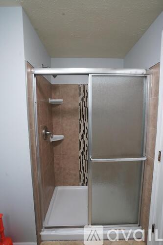 A shower stall with a glass door and a white bench seat.