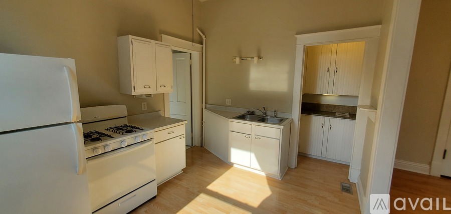 A kitchen with white appliances and cabinets is available for rent.