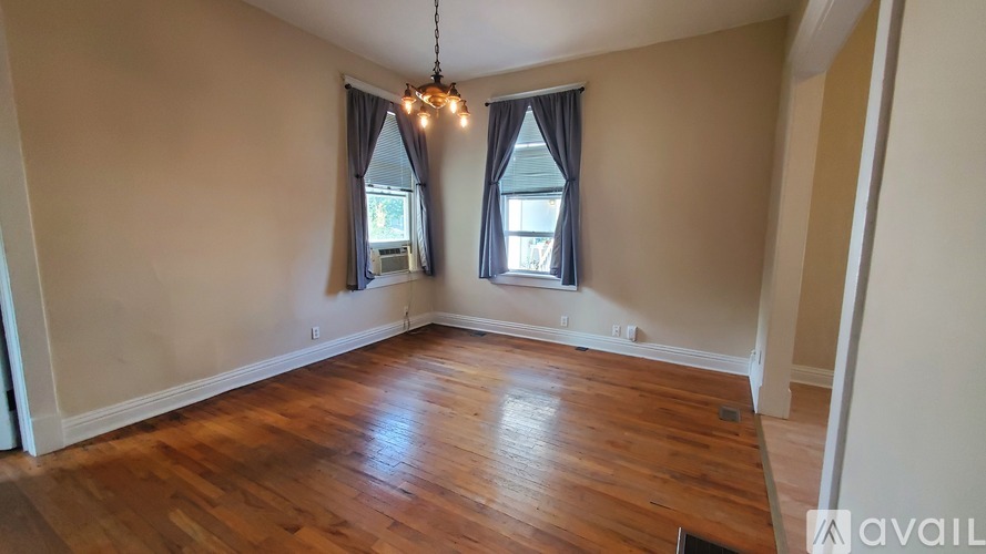 A room with wooden floors and a window with curtains.