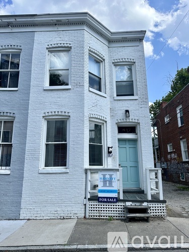 A two-story house with a blue door and a "For Sale" sign in front.