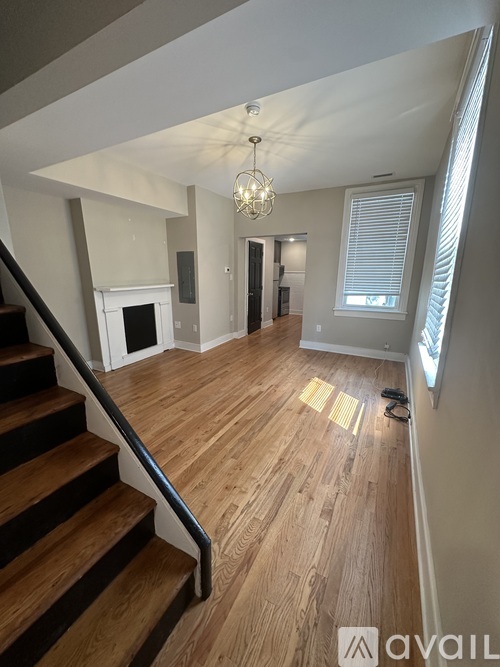 A wooden staircase with a metal handrail leads up to a brightly lit living room.