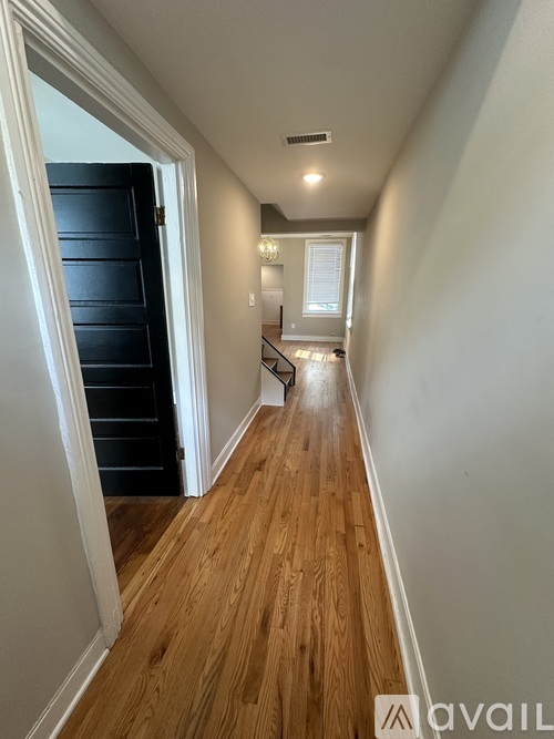 A long hallway with wood floors and white walls.