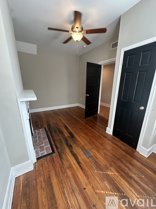A room with a ceiling fan and wooden floors.