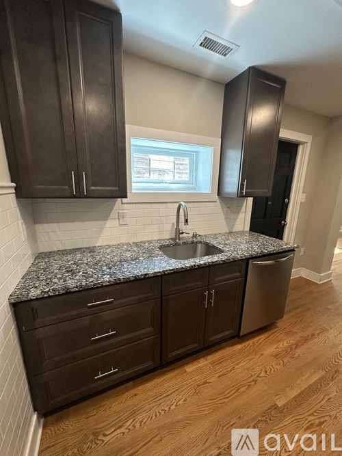 A kitchen with dark brown cabinets and granite countertops.