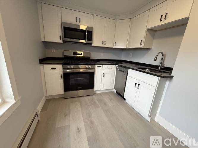 A kitchen with white cabinets and a wooden floor.