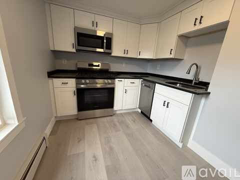 A kitchen with white cabinets and a wooden floor.