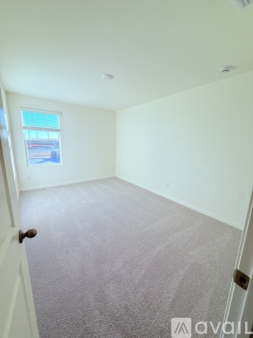 A room with a carpeted floor and a window with blinds.