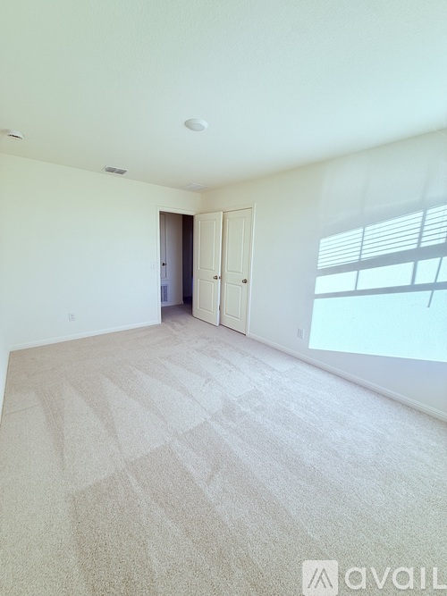 A carpeted room with a doorway leading to another room.